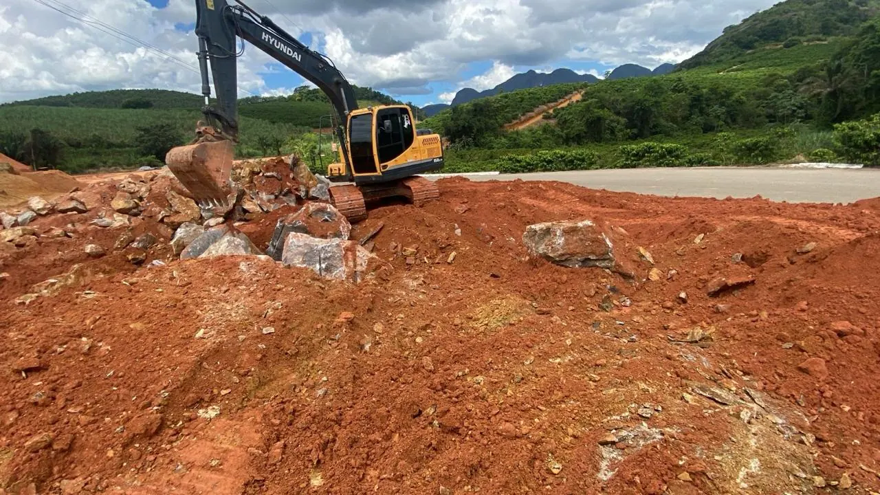 Escavadeira removendo a rocha fragmentada a frio no terreno terraplenado