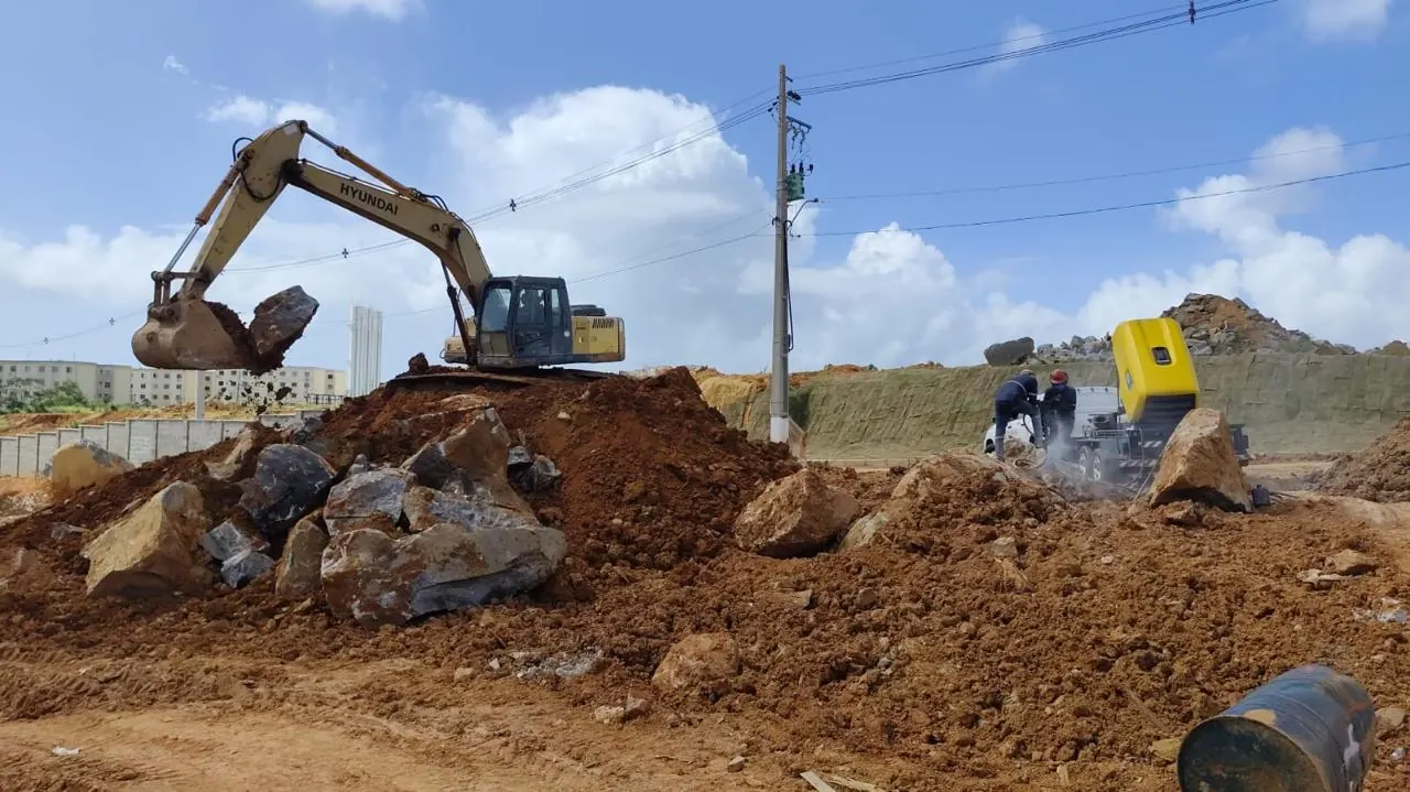 Desmonte de rocha em área urbana com a obra em andamento ao redor