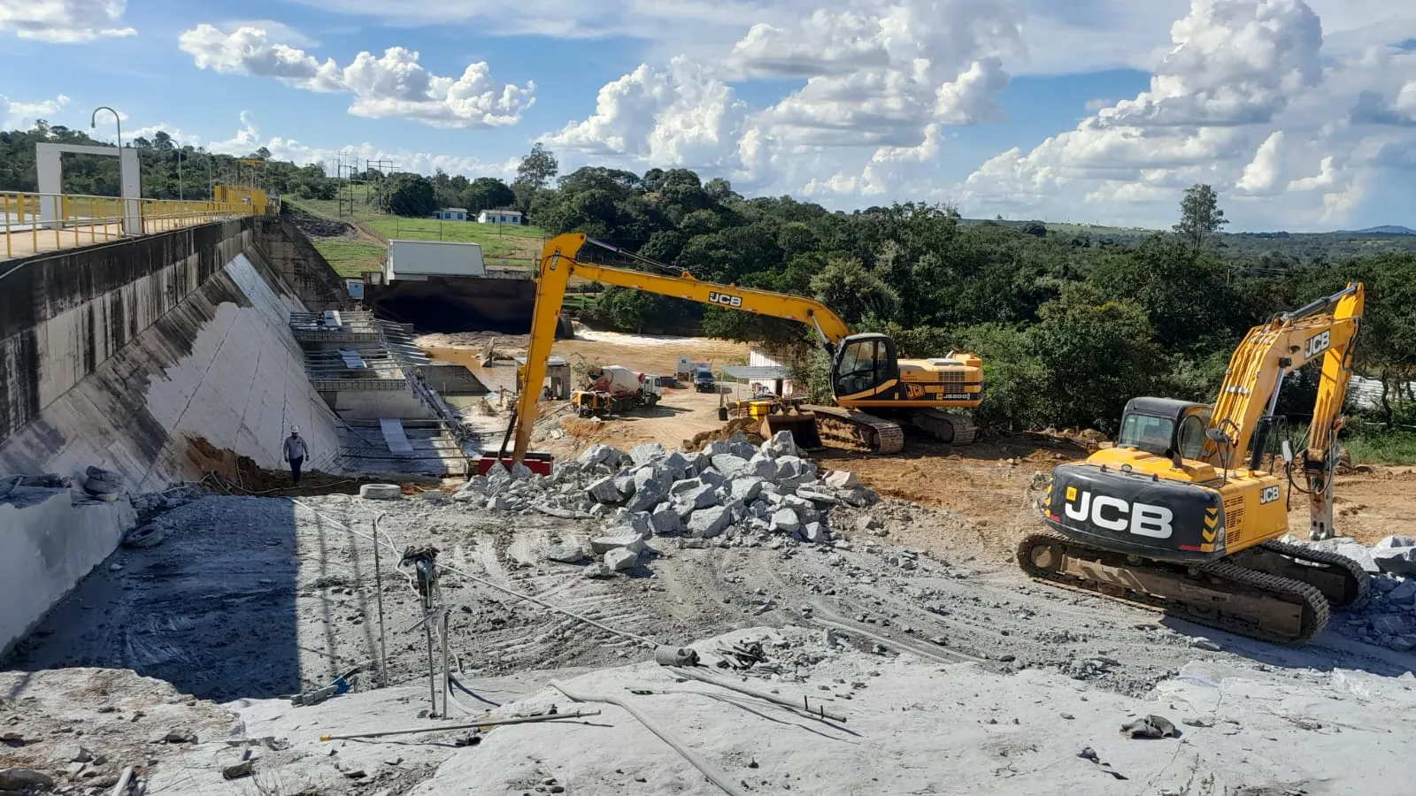 Duas escavadeiras JCB operando junto &agrave; parede da barragem da PCH Cajuru