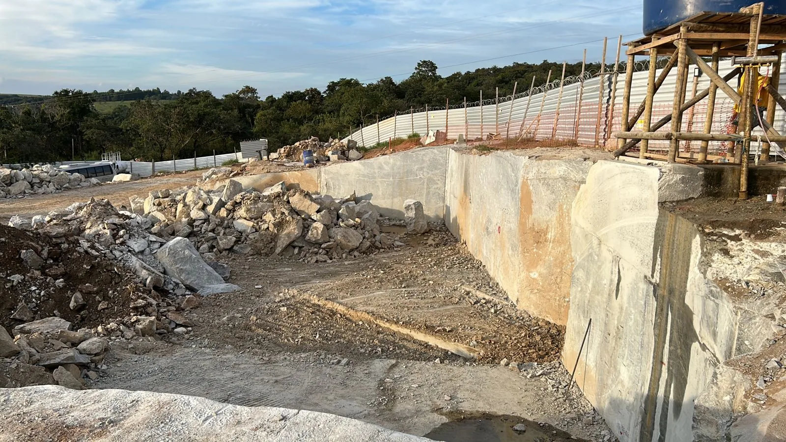 Escava&ccedil;&atilde;o de rocha rente &agrave; parede de concreto da barragem da PCH Cajuru
