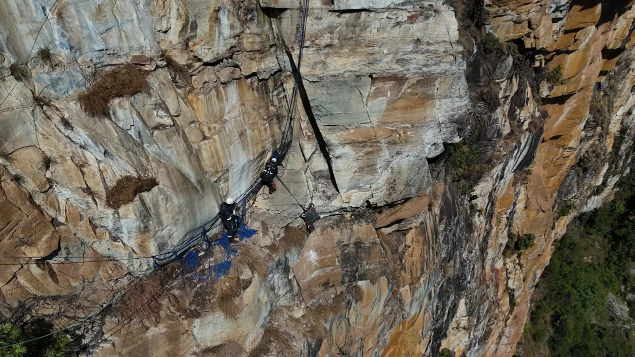 Alpinista industrial em rapel durante o serviço de bate-choco no paredão